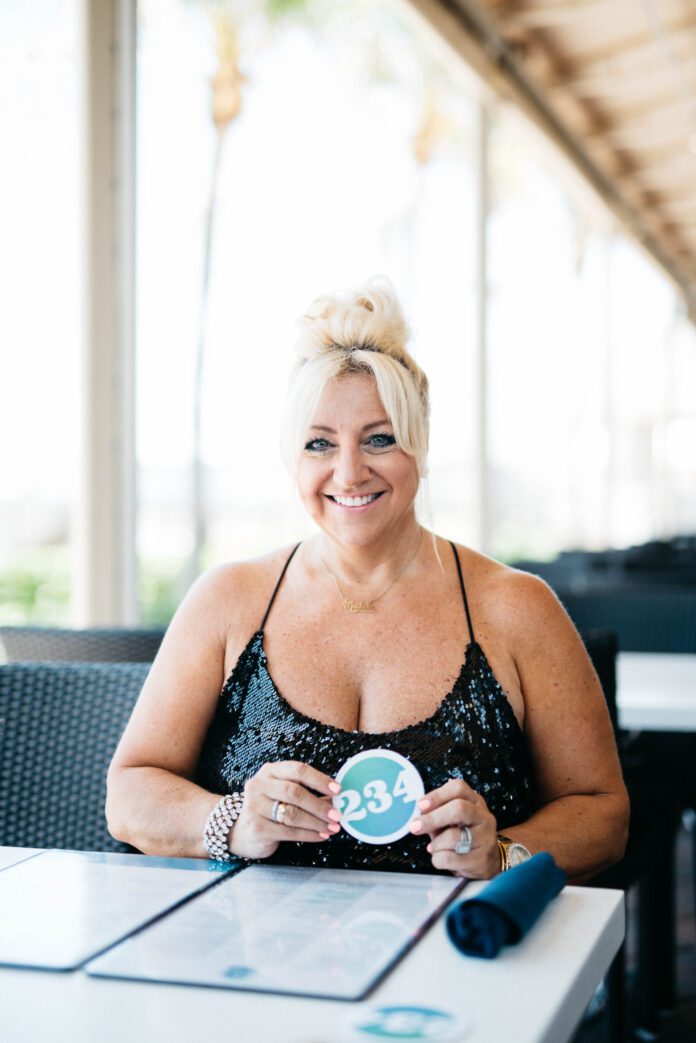 Woman holding number card at outdoor restaurant.