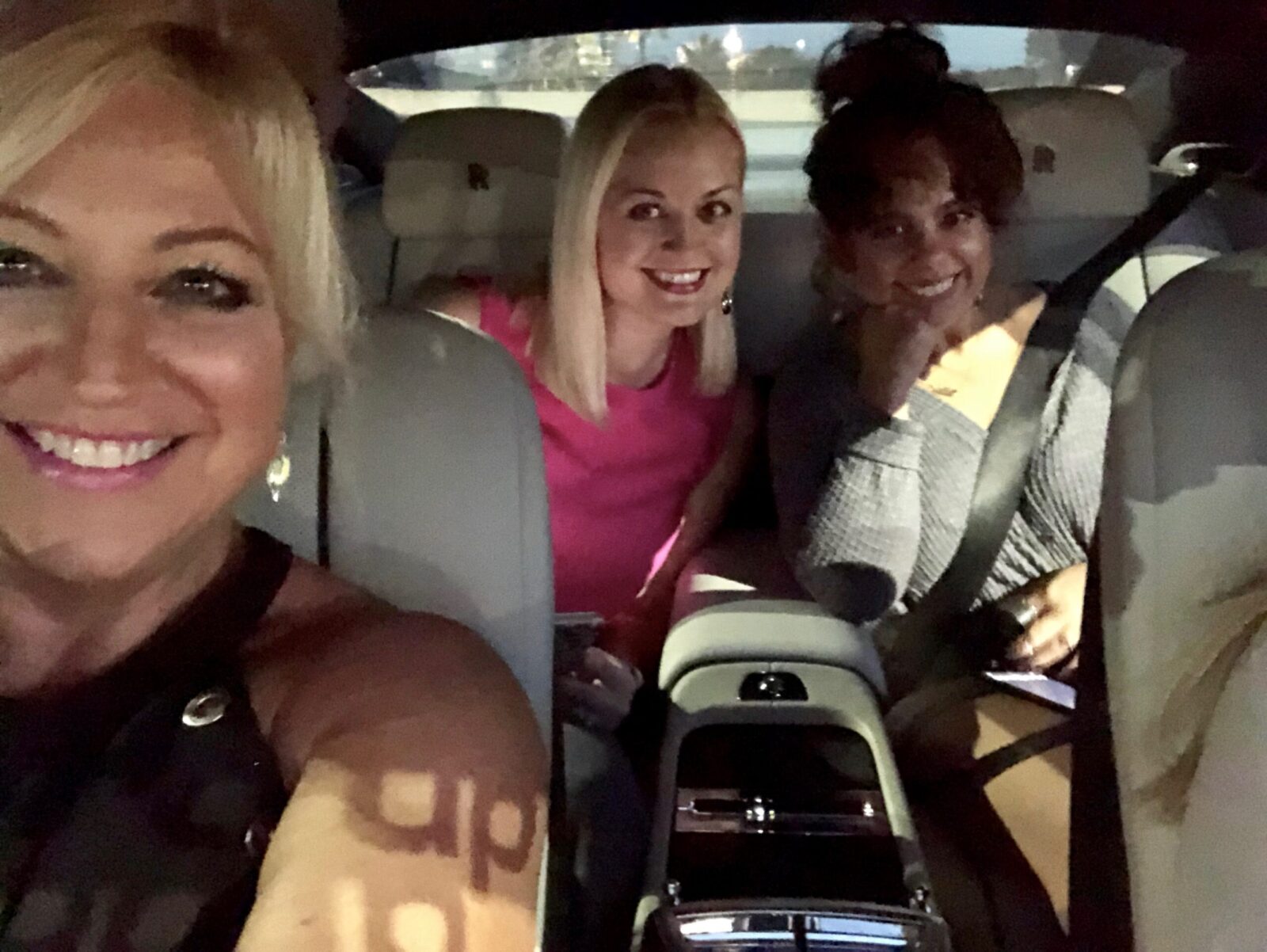 Three women smiling inside a car at night. - #SoooBoca® Florida Lifestyle